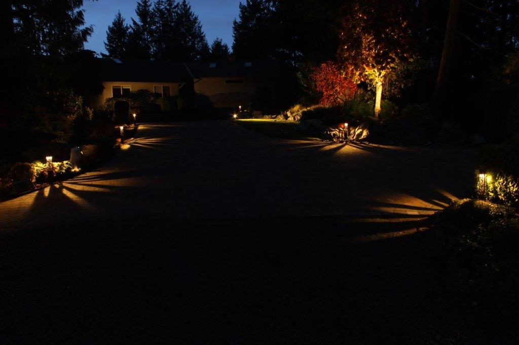 Long driveway lit at night using landscape lights.